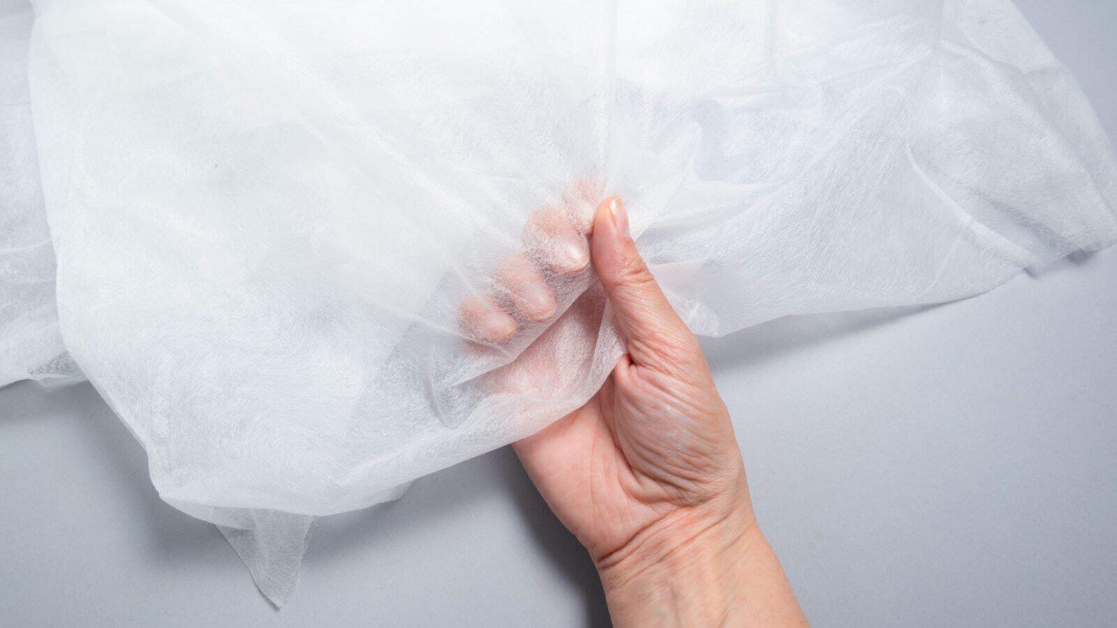 Close up view of a man holding a white non-woven fabric plant cover